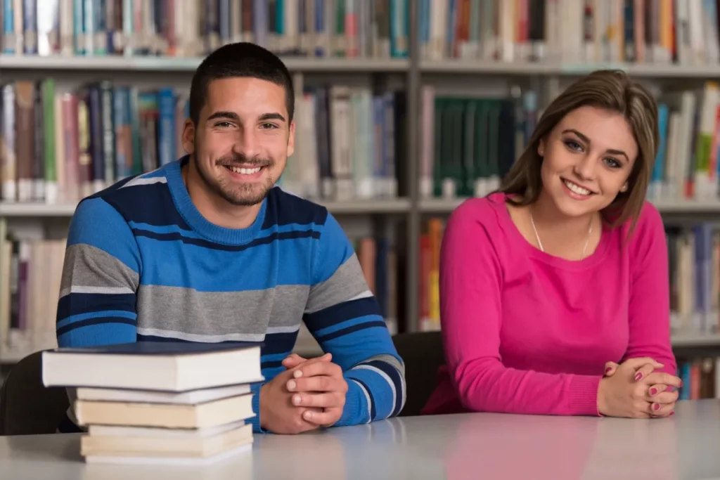 Students sitting and smiling at a table in a library.